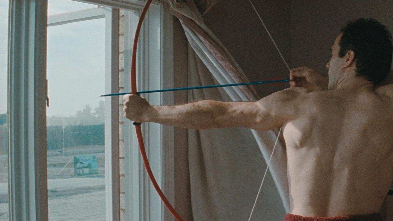 a man aiming a bow and arrow out a window